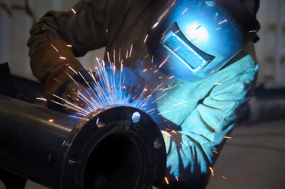 pipe welder at work wearing full gear
